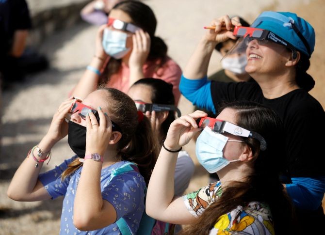People use protective glasses to observe a partial solar eclipse from Mount Scopus in Jerusalem June 21, 2020. REUTERS